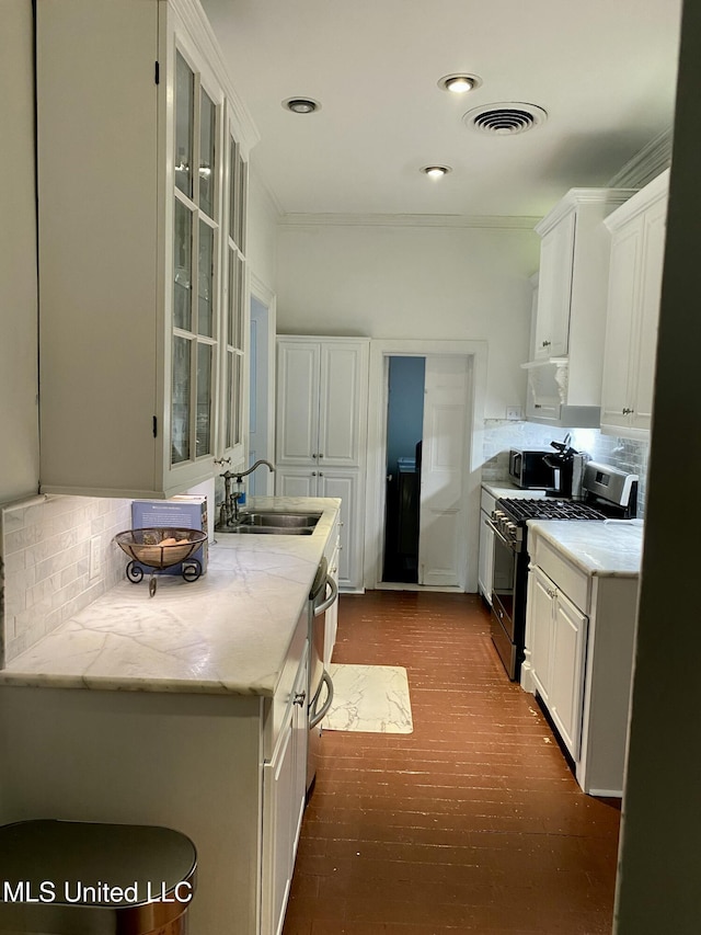 kitchen with a sink, visible vents, white cabinets, gas stove, and glass insert cabinets