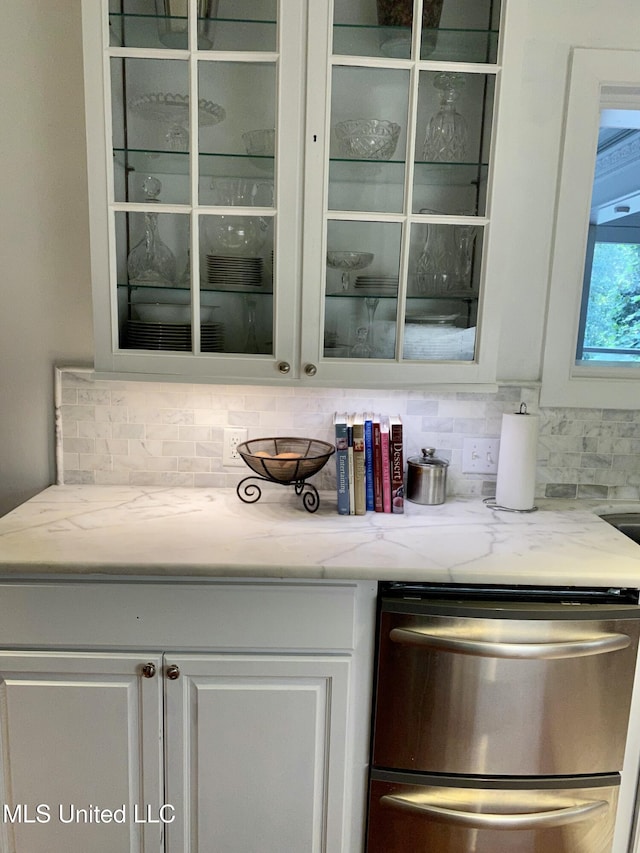 bar featuring stainless steel dishwasher and backsplash