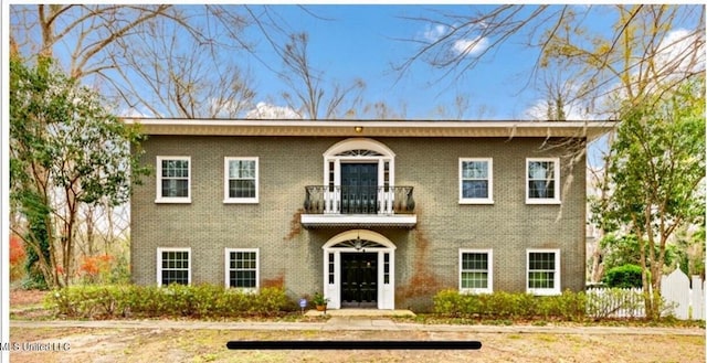 view of front facade with brick siding and a balcony