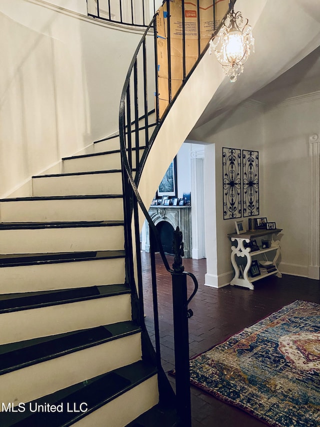 stairway with baseboards, wood finished floors, a towering ceiling, and an inviting chandelier