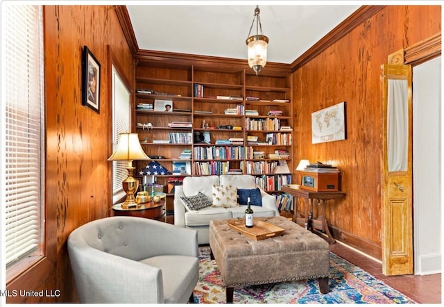 sitting room with wood walls, baseboards, built in shelves, and ornamental molding