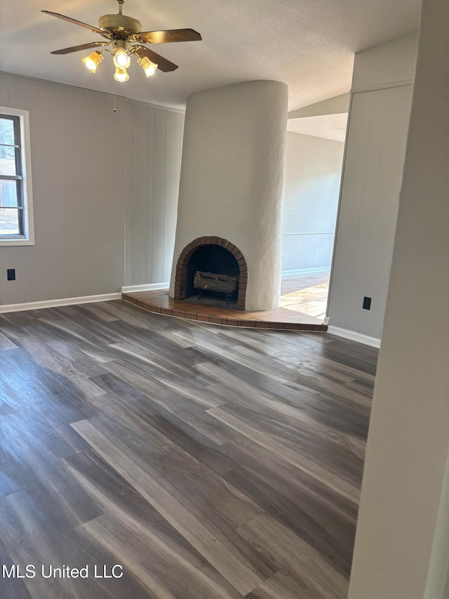 unfurnished living room featuring vaulted ceiling, a brick fireplace, ceiling fan, and dark wood-type flooring