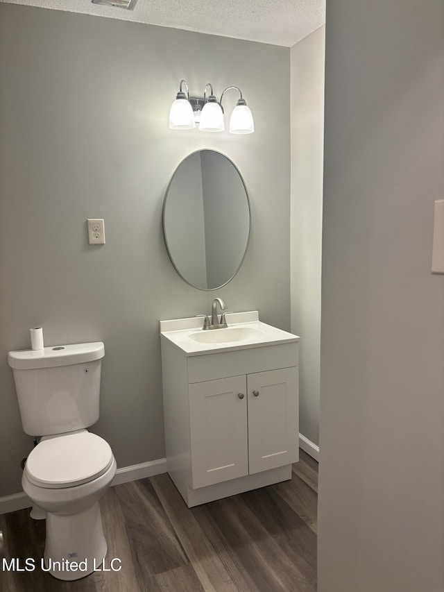 bathroom with vanity, toilet, wood-type flooring, and a textured ceiling