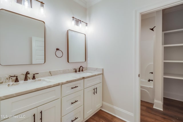 bathroom featuring double vanity, wood finished floors, and a sink