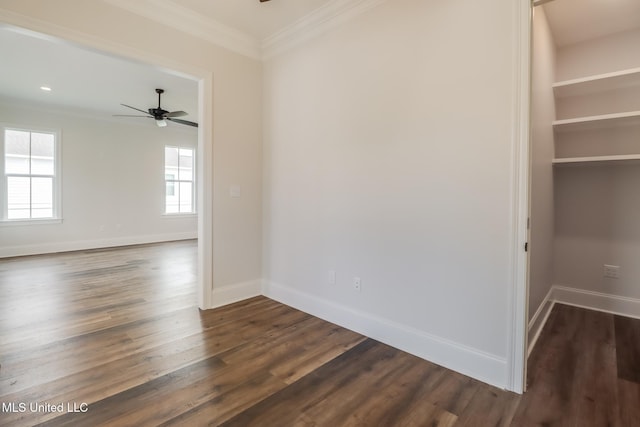 empty room with ceiling fan, ornamental molding, dark wood-style flooring, and baseboards