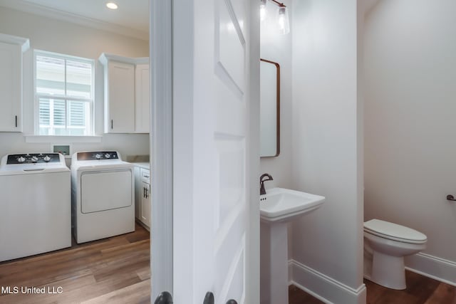 half bathroom featuring baseboards, wood finished floors, toilet, and washer and dryer