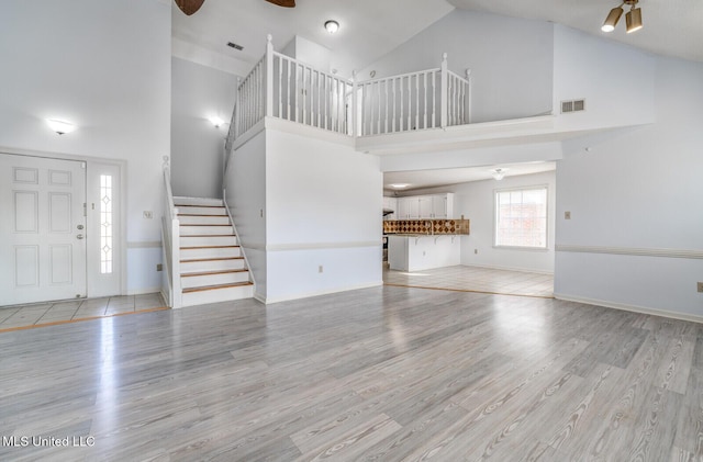 unfurnished living room featuring light hardwood / wood-style floors, high vaulted ceiling, and ceiling fan