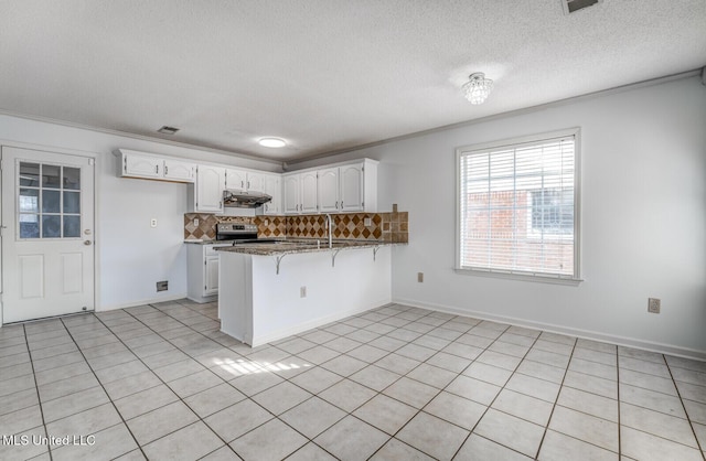 kitchen featuring a breakfast bar, white cabinets, stainless steel electric range oven, tasteful backsplash, and kitchen peninsula