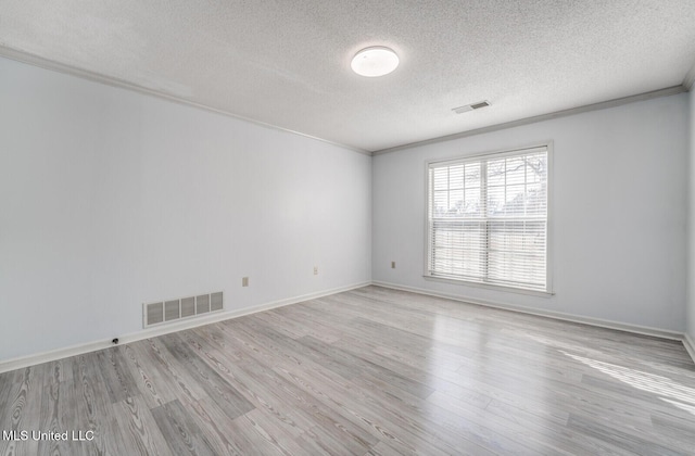 empty room featuring a textured ceiling, light hardwood / wood-style flooring, and ornamental molding