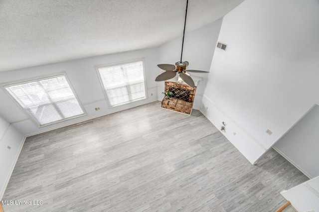 living room featuring ceiling fan, light hardwood / wood-style floors, and a textured ceiling