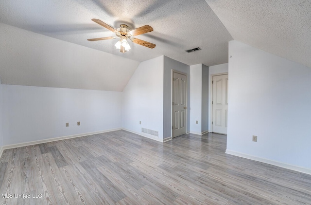 bonus room featuring ceiling fan, light wood-type flooring, a textured ceiling, and vaulted ceiling