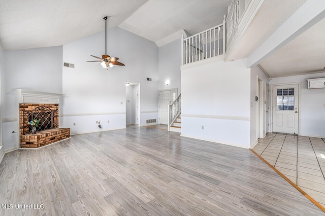 unfurnished living room with hardwood / wood-style flooring, ceiling fan, a fireplace, and high vaulted ceiling