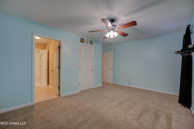 unfurnished bedroom with ceiling fan, ensuite bathroom, and light carpet