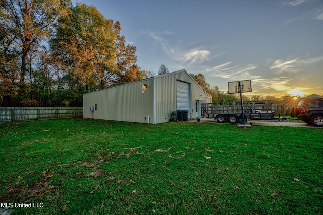 property exterior at dusk with a lawn and an outbuilding