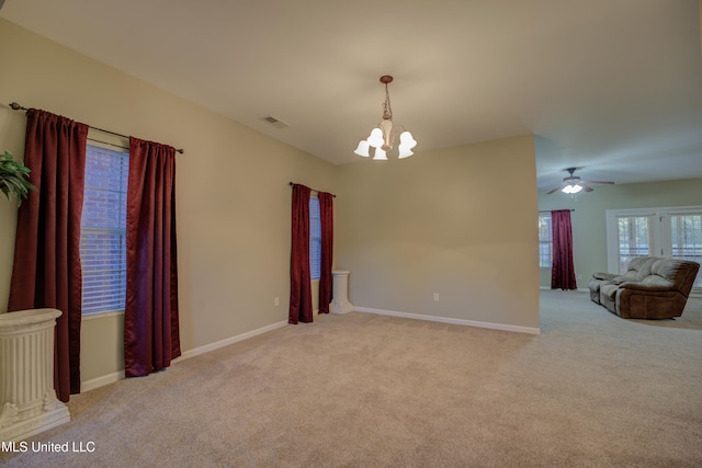 carpeted empty room featuring ceiling fan with notable chandelier