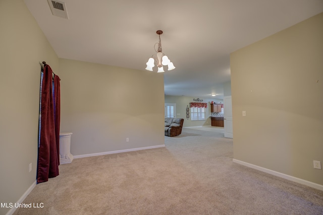 carpeted spare room featuring a chandelier