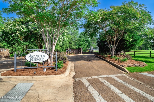 6147 Wirtz Rd, Flowood, MS 39232 - view of asphalt road with curbs, view of wooded area, and a gated entry