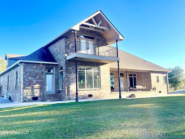 rear view of house featuring a balcony and a lawn