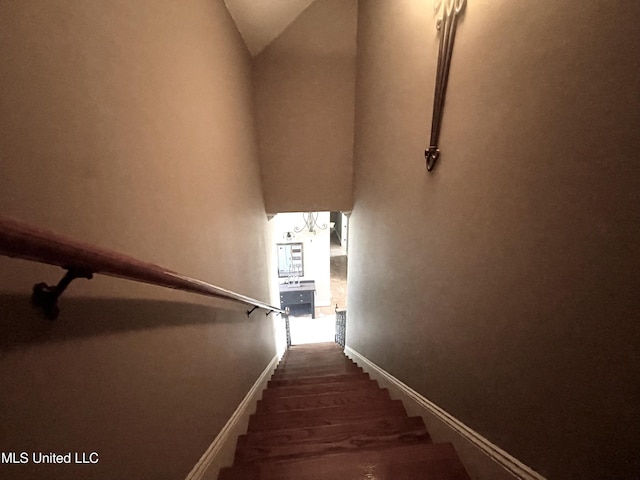 staircase with hardwood / wood-style floors and vaulted ceiling