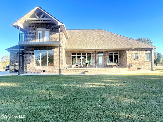 rear view of house with a balcony and a yard