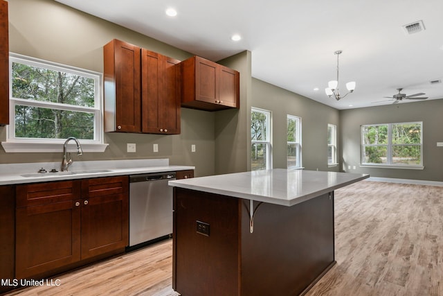 kitchen featuring sink, dishwasher, a breakfast bar area, hanging light fixtures, and light hardwood / wood-style flooring