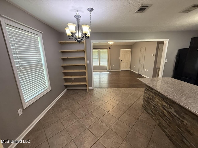 22090 Rayvan Ln, Kiln, MS 39556 - unfurnished dining area featuring a chandelier, dark tile patterned floors, and a textured ceiling