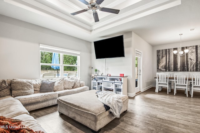 living area with wood finished floors, a healthy amount of sunlight, visible vents, and a raised ceiling