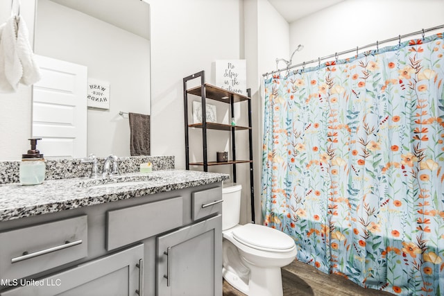 bathroom with curtained shower, toilet, vanity, and wood finished floors