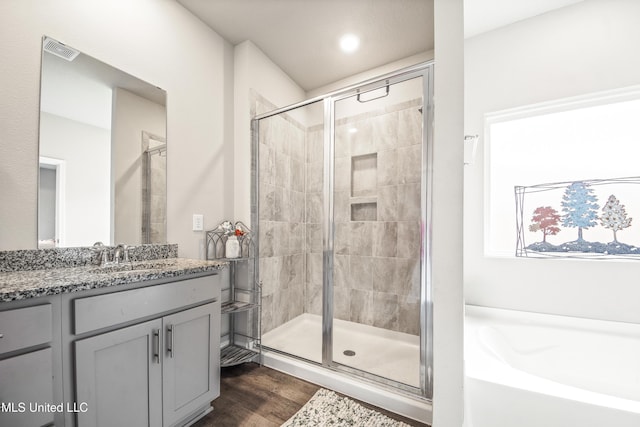 bathroom with visible vents, wood finished floors, a garden tub, and a stall shower