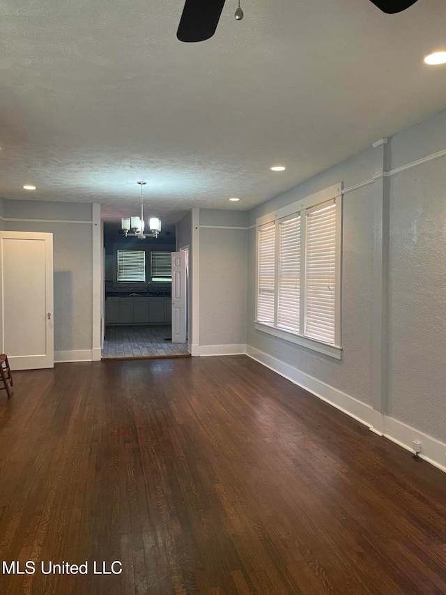 unfurnished living room featuring dark hardwood / wood-style floors and an inviting chandelier