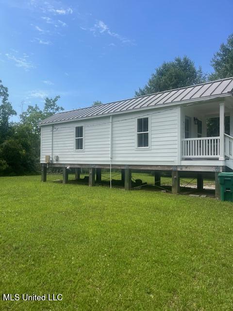 909 Sears Ave, Waveland, MS 39576 - view of side of property with a lawn, metal roof, and a standing seam roof