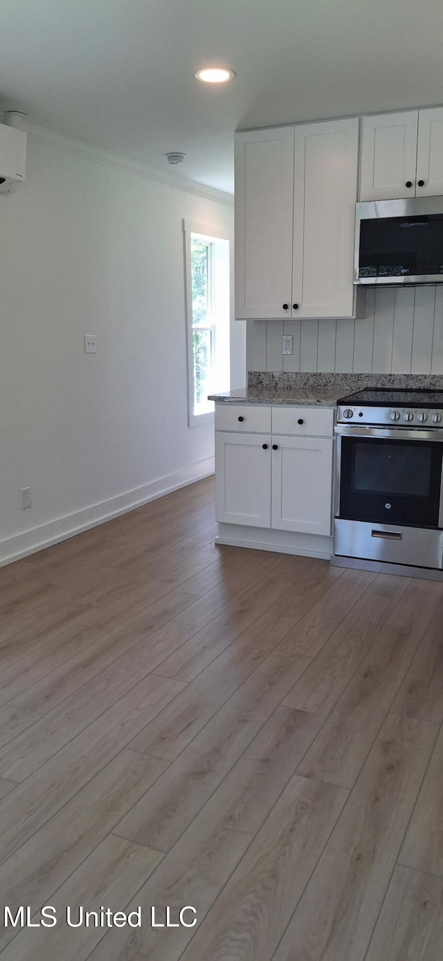 909 Sears Ave, Waveland, MS 39576 - kitchen with appliances with stainless steel finishes, ornamental molding, white cabinets, light wood-type flooring, and baseboards