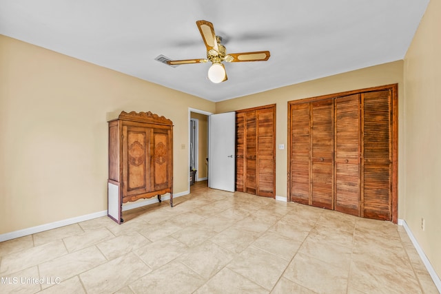 unfurnished bedroom with multiple closets and ceiling fan