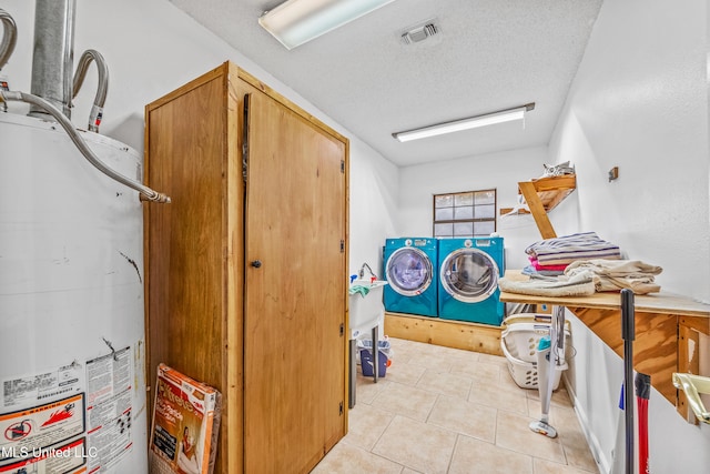 laundry area with light tile patterned flooring, a textured ceiling, and gas water heater