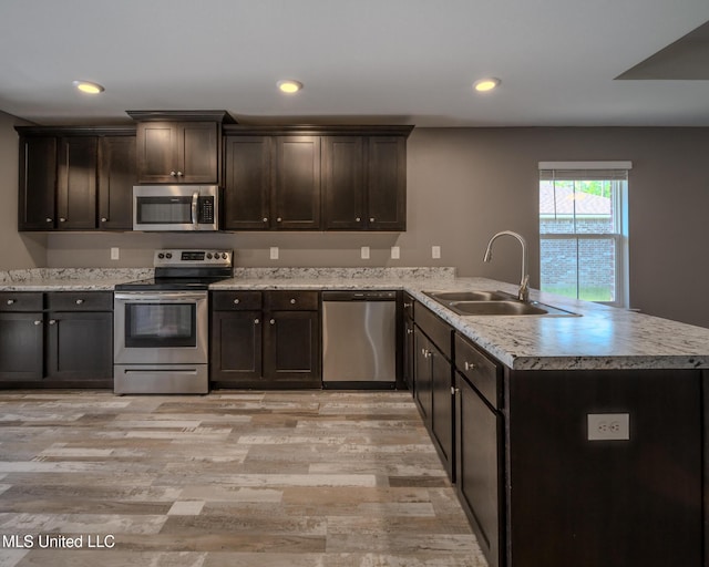 13724 Fox Hill Dr, Gulfport, MS 39503 - kitchen featuring appliances with stainless steel finishes, a sink, a peninsula, light wood finished floors, and dark brown cabinetry