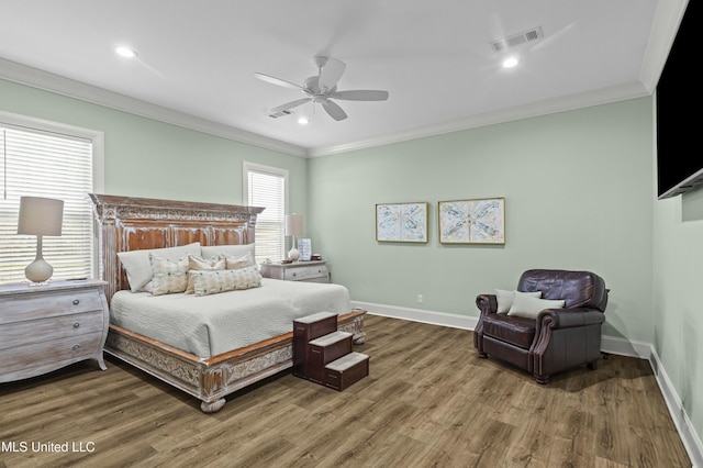 bedroom with visible vents, baseboards, wood finished floors, and crown molding