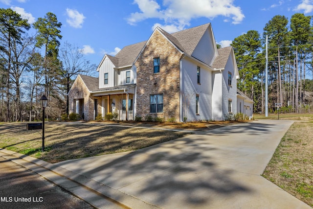 view of front of property featuring concrete driveway, brick siding, a front yard, and roof with shingles