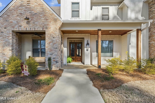 view of exterior entry featuring french doors, brick siding, and board and batten siding