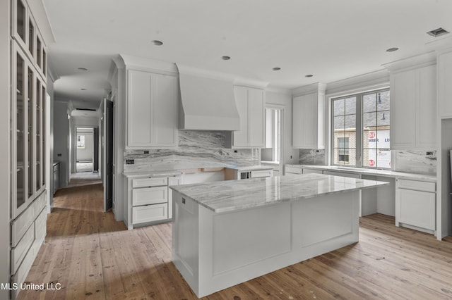 230 Parke Dr, Ridgeland, MS 39157 - kitchen with custom range hood, light wood-style flooring, light stone counters, and tasteful backsplash