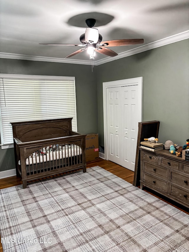 503 E Adams Ave, Greenwood, MS 38930 - bedroom featuring wood finished floors, ornamental molding, a closet, ceiling fan, and a crib