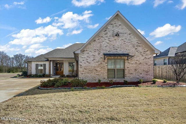 view of front of property with brick siding, a front yard, and fence