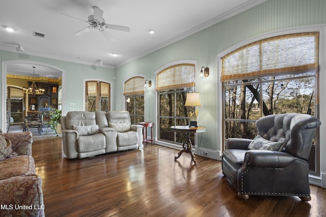 living room with ceiling fan with notable chandelier, crown molding, wood finished floors, and visible vents