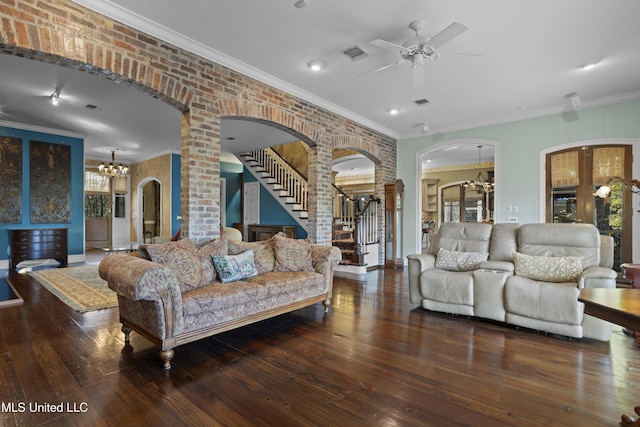 living room featuring visible vents, hardwood / wood-style floors, arched walkways, brick wall, and stairs