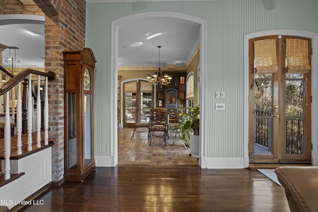 entrance foyer with baseboards, an inviting chandelier, dark wood-style flooring, arched walkways, and french doors
