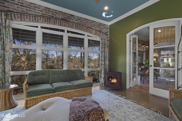 living area featuring wood finished floors, brick wall, a wood stove, recessed lighting, and ornamental molding