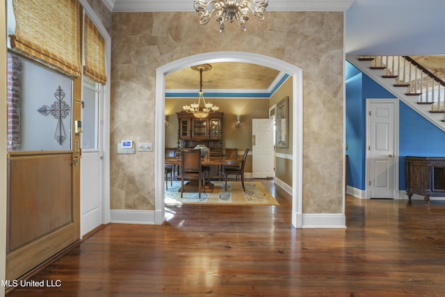 foyer entrance with hardwood / wood-style floors, arched walkways, a high ceiling, baseboards, and a chandelier