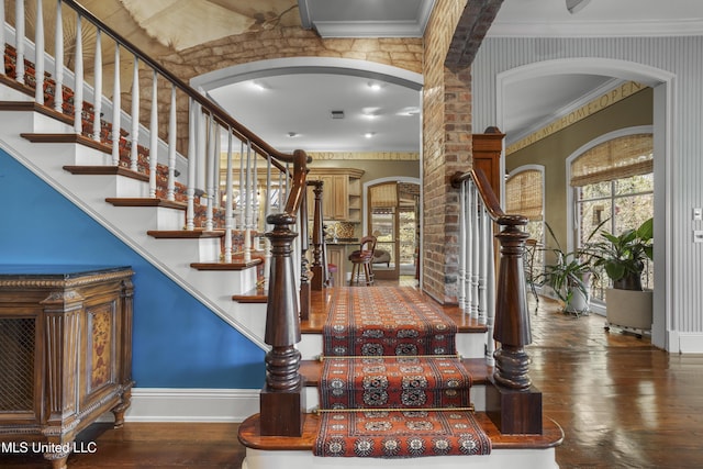 foyer entrance with arched walkways, plenty of natural light, wood-type flooring, and ornamental molding