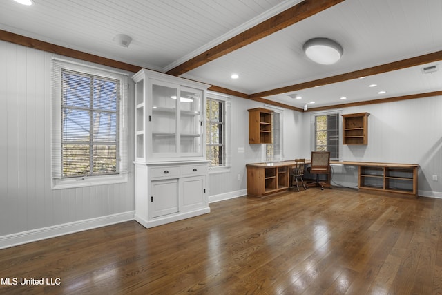 unfurnished office featuring beam ceiling, a wealth of natural light, built in desk, and wood-type flooring