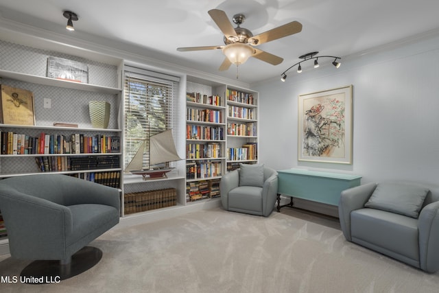 sitting room featuring carpet flooring, crown molding, and a ceiling fan