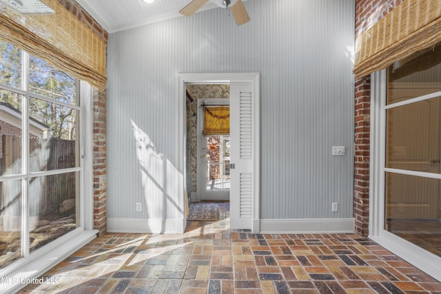 interior space featuring brick floor, baseboards, and ceiling fan